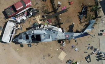 Overturned military helicopter crushing vehicles after crash in residential area