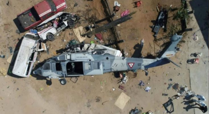 Overturned military helicopter crushing vehicles after crash in residential area