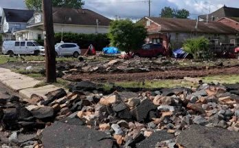 Damaged residential street with rubble and houses