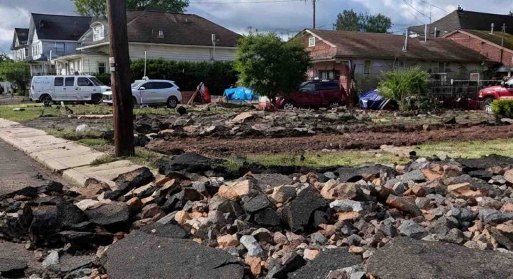 Damaged residential street with rubble and houses