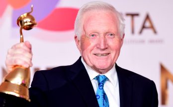 Man holding golden bell-shaped trophy