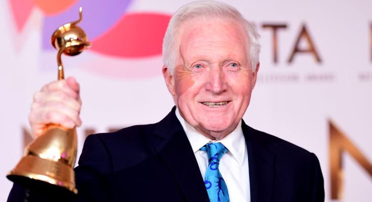 Man holding golden bell-shaped trophy