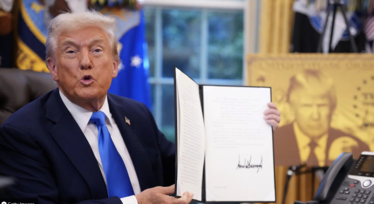 Trump holds a signed executive order during an Oval Office appearance.