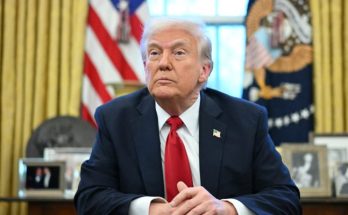 former President Donald Trump seated in the Oval Office with American flag and