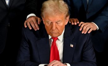Trump looking down with hands on shoulders