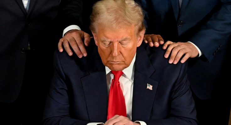 Trump looking down with hands on shoulders