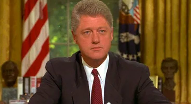 president Bill Clinton seated at Oval Office desk with American flag and busts in