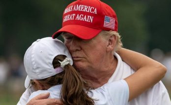 man in red hat embraces young girl outdoors, expressing warmth