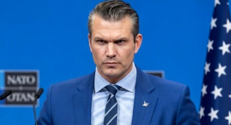 man in blue suit speaking at NATO event, serious expression