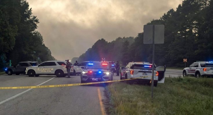 police cars with flashing lights block road amid early morning mist