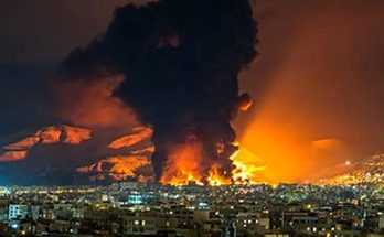 massive fireball and smoke plume erupting over a city skyline at night