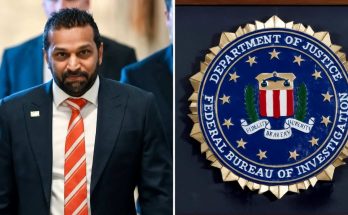 man in suit and red tie stands beside FBI seal in official setting