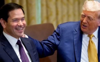 former Florida Governor Ron DeSantis laughs as former President Donald Trump places his