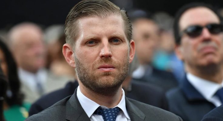 man in suit at formal event, serious expression, blurred crowd