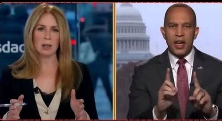 news anchors in studio, one gesturing, Capitol Building visible behind other anchor