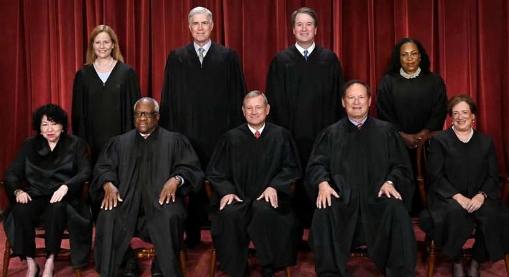 supreme Court justices in formal robes against red curtain backdrop