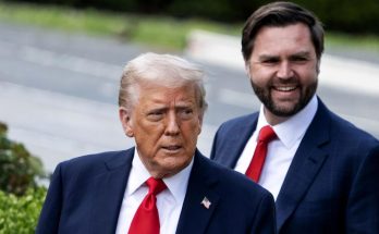 donald Trump and Ron DeSantis walking outdoors in suits with red ties, American flag pin