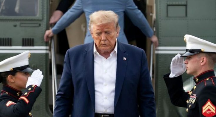 former President Donald Trump descends steps from a military transport plane as two