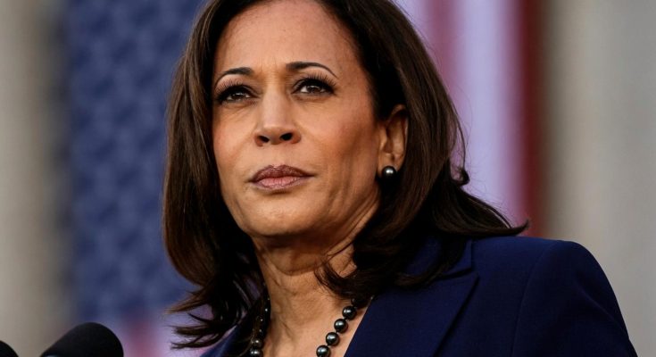 confident woman speaks at podium with USA flag backdrop