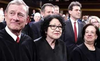 three Supreme Court justices in black robes stand together in a formal courtroom setting