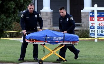 police officers moving covered stretcher outside house for sale