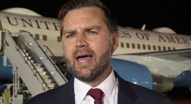 man in suit and red tie speaking in front of a United States of America airplane at night