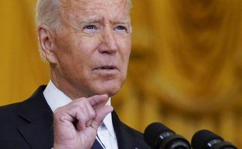 president Joe Biden speaking at podium with microphones, gesturing with finger raised