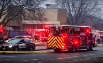 fire truck with chevron stripes and police car behind yellow tape at emergency scene near