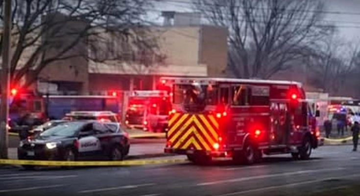fire truck with chevron stripes and police car behind yellow tape at emergency scene near