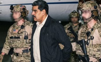 man in custody escorted by armed DEA agents near aircraft