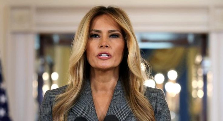 melania Trump speaking at a press conference in the White House with American flag visible